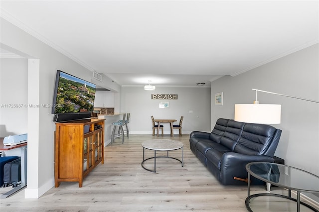 living area featuring light wood-type flooring, baseboards, visible vents, and ornamental molding