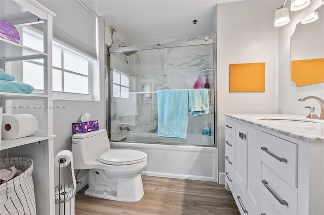 bathroom with shower / bath combination with glass door, vanity, toilet, and wood finished floors