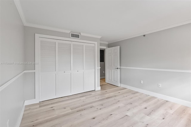 unfurnished bedroom featuring a closet, light wood-type flooring, visible vents, and crown molding