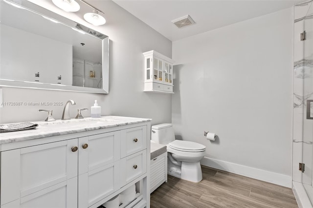 bathroom featuring baseboards, visible vents, toilet, wood finished floors, and vanity