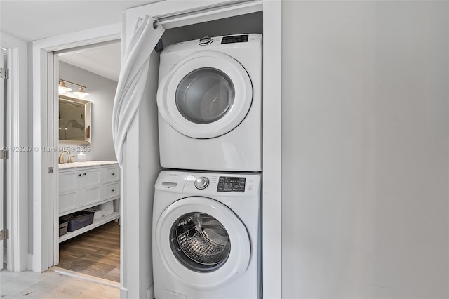 laundry room with stacked washer and dryer, light wood-style flooring, and laundry area