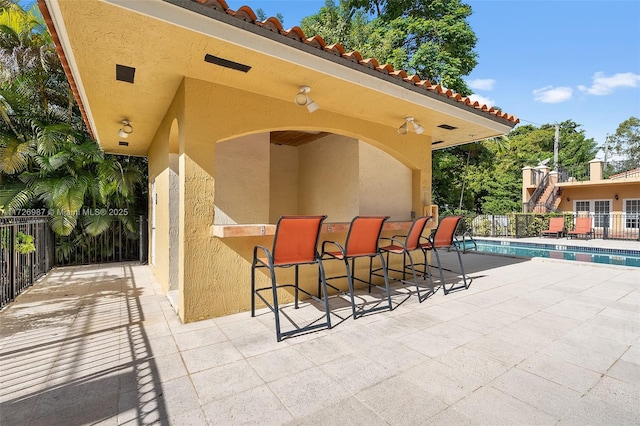 view of patio / terrace with fence, outdoor dry bar, and a fenced in pool