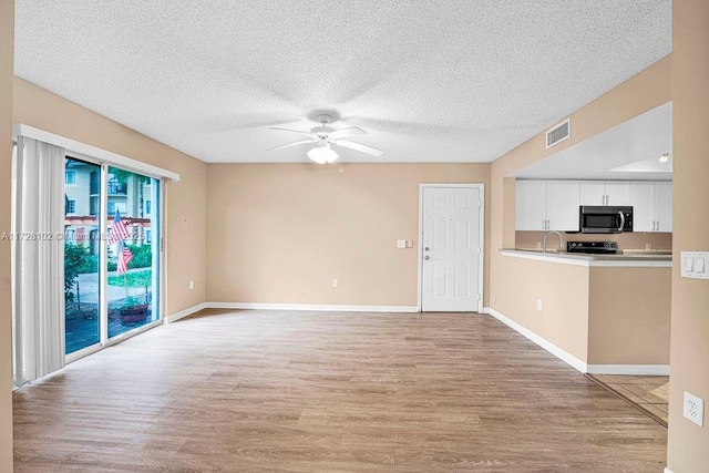 unfurnished living room featuring ceiling fan, sink, a textured ceiling, and light hardwood / wood-style flooring