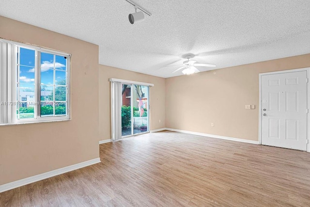 unfurnished room featuring a textured ceiling, plenty of natural light, and light hardwood / wood-style flooring