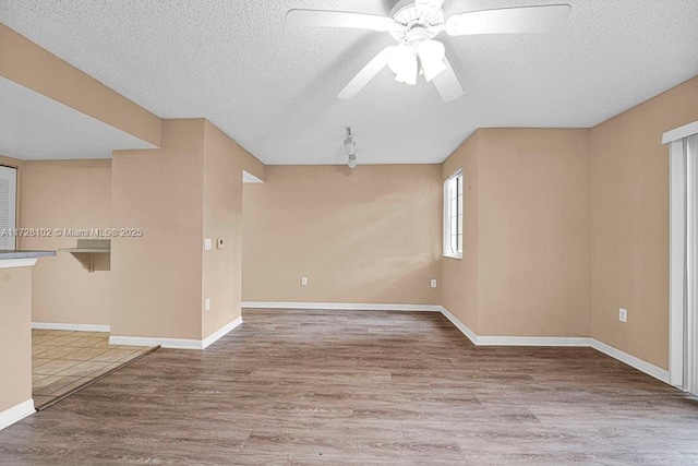 empty room with ceiling fan, a textured ceiling, and hardwood / wood-style floors