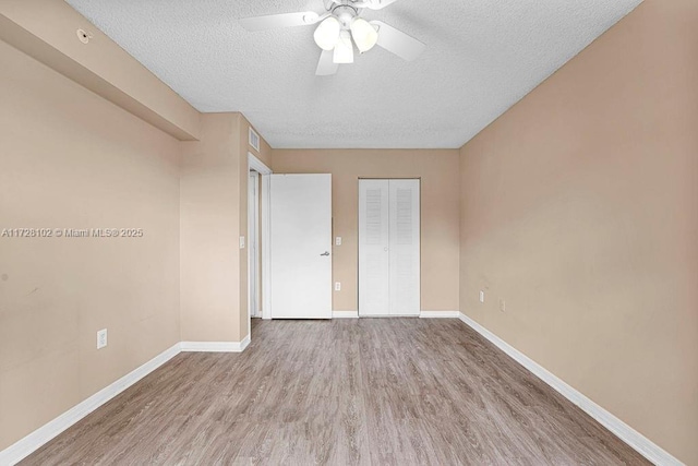 unfurnished bedroom with ceiling fan, hardwood / wood-style floors, a closet, and a textured ceiling