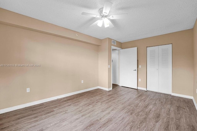 unfurnished bedroom with ceiling fan, a closet, a textured ceiling, and hardwood / wood-style flooring