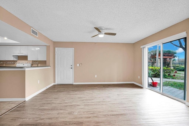 unfurnished living room with ceiling fan, a textured ceiling, and light hardwood / wood-style flooring