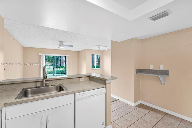 kitchen featuring a textured ceiling, white cabinets, sink, light tile patterned flooring, and white dishwasher