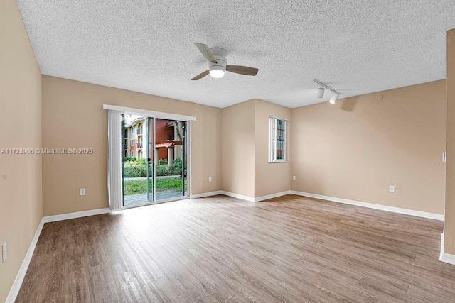 spare room featuring a textured ceiling, ceiling fan, rail lighting, and wood-type flooring