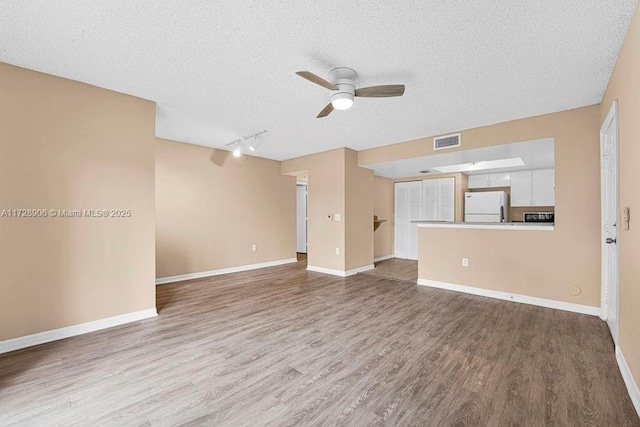 unfurnished living room featuring wood-type flooring, a textured ceiling, and ceiling fan