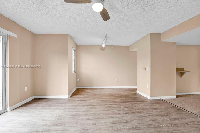 spare room featuring a textured ceiling, ceiling fan, track lighting, and light hardwood / wood-style floors