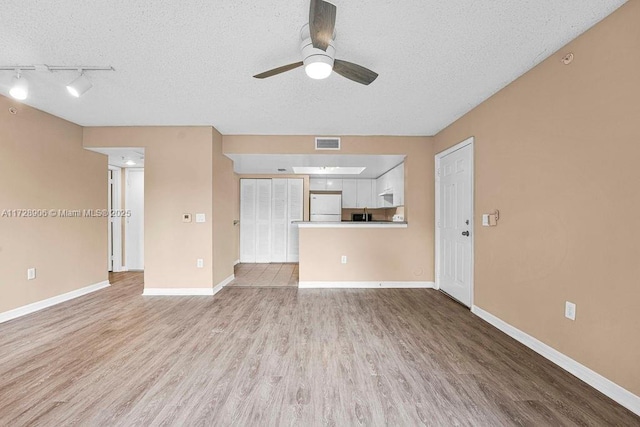 unfurnished living room with a textured ceiling, ceiling fan, track lighting, and light hardwood / wood-style floors