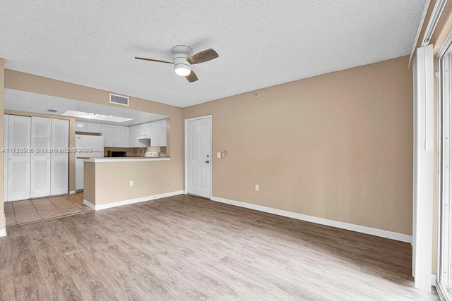 unfurnished living room featuring ceiling fan, a textured ceiling, and light wood-type flooring