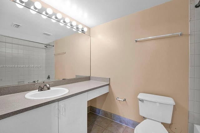 bathroom featuring toilet, tile patterned flooring, a tile shower, and vanity