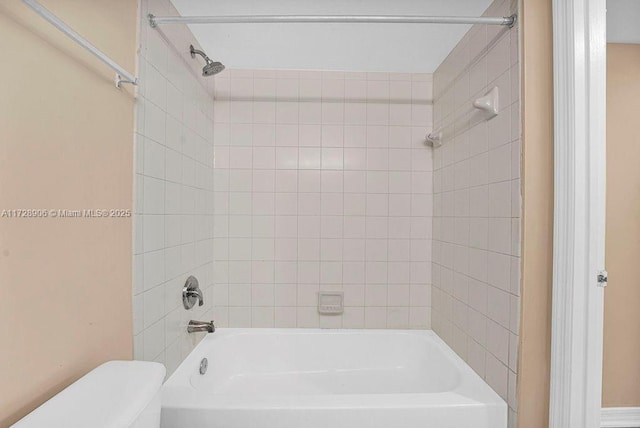 bathroom featuring toilet and tiled shower / bath