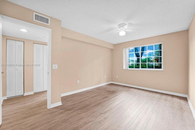 unfurnished room featuring light wood-type flooring, ceiling fan, and a textured ceiling