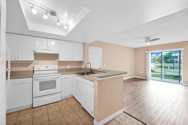 kitchen featuring light tile patterned floors, white cabinetry, a raised ceiling, white appliances, and sink