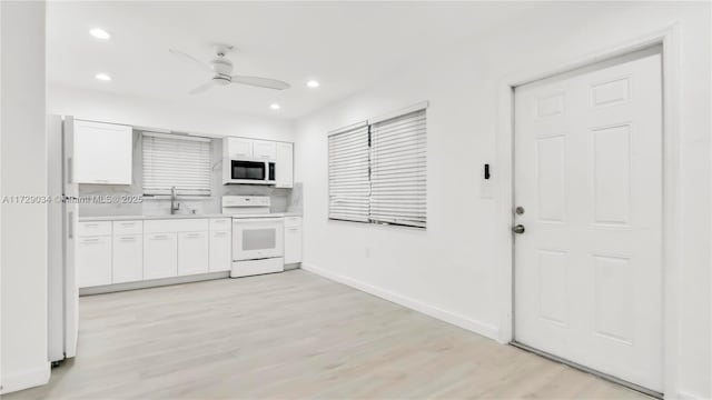 kitchen featuring white appliances, white cabinetry, sink, light wood-type flooring, and ceiling fan