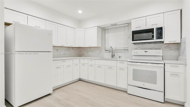 kitchen with white cabinetry, sink, and white appliances