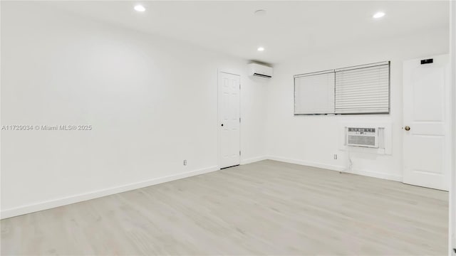 unfurnished room with light wood-type flooring and a wall mounted air conditioner