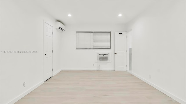 empty room with light wood-type flooring and a wall mounted AC