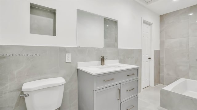 bathroom with toilet, vanity, tile walls, and a bathing tub