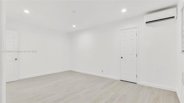 unfurnished room featuring a wall mounted AC and light hardwood / wood-style flooring