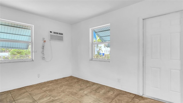 tiled spare room featuring an AC wall unit