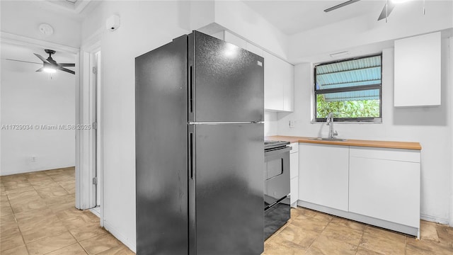 kitchen with black fridge, ceiling fan, white cabinetry, and sink