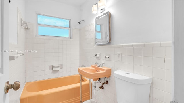 bathroom featuring tile walls, tiled shower / bath combo, and toilet