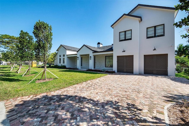 view of front of house with a garage, a front lawn, decorative driveway, and stucco siding