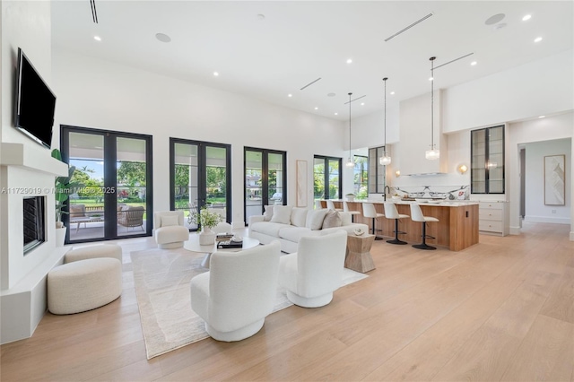 11001 SW 74th Ave, Pinecrest, FL 33156 - living room featuring a high ceiling, light wood-type flooring, french doors, a fireplace with raised hearth, and recessed lighting