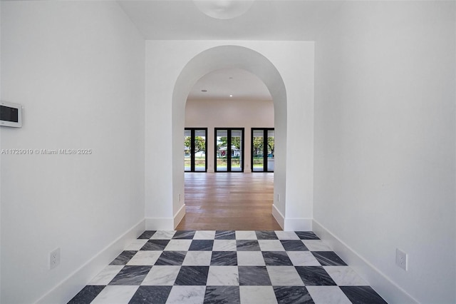 hallway with baseboards and arched walkways