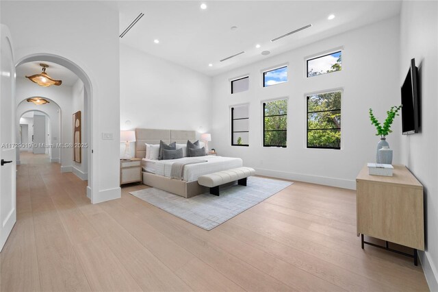 11001 SW 74th Ave, Pinecrest, FL 33156 - bedroom featuring arched walkways, a towering ceiling, light wood-type flooring, recessed lighting, and baseboards