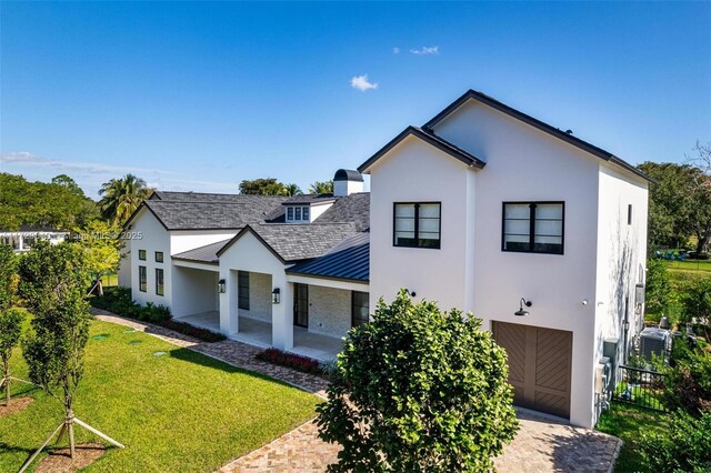 11001 SW 74th Ave, Pinecrest, FL 33156 - view of front of home featuring a standing seam roof, an attached garage, stucco siding, metal roof, and decorative driveway