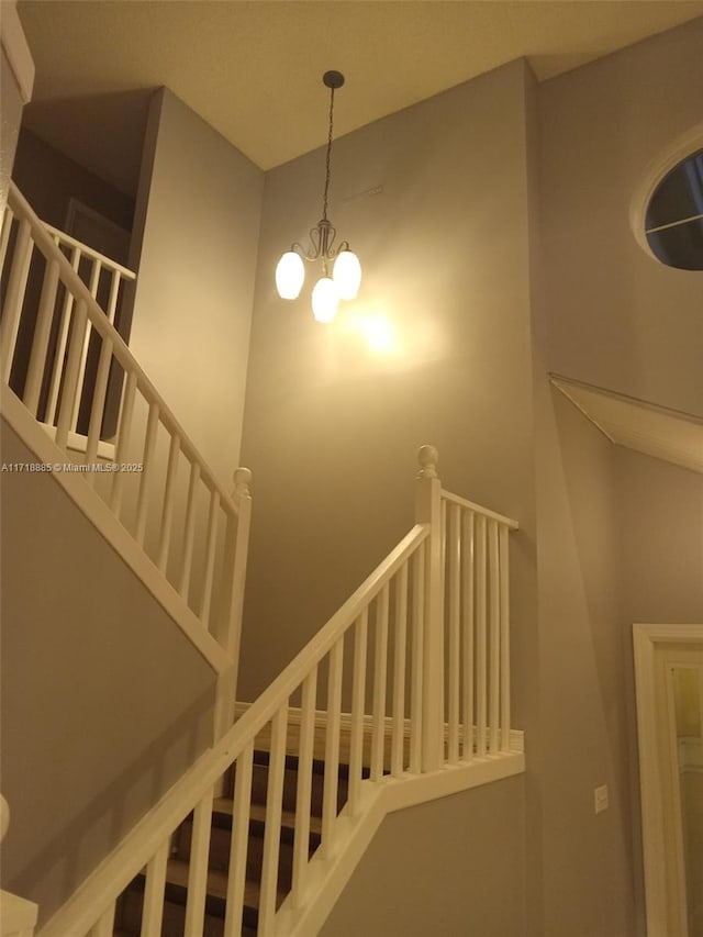 stairs with a towering ceiling and an inviting chandelier