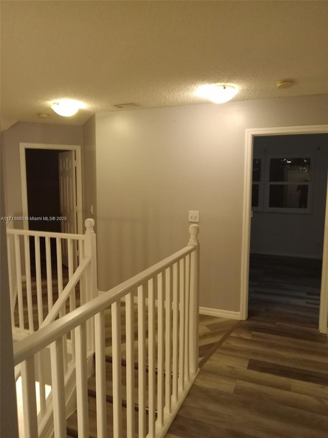 corridor with a textured ceiling and dark hardwood / wood-style flooring