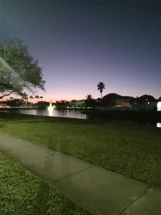 yard at dusk featuring a water view