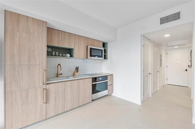 kitchen featuring light stone countertops, appliances with stainless steel finishes, sink, backsplash, and light brown cabinets