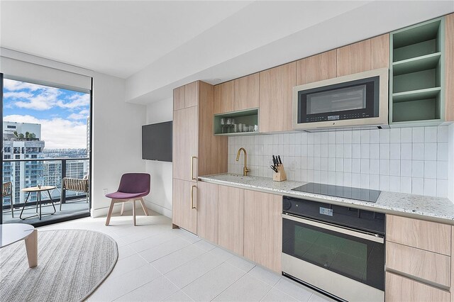 kitchen featuring sink, light stone counters, appliances with stainless steel finishes, and light brown cabinets