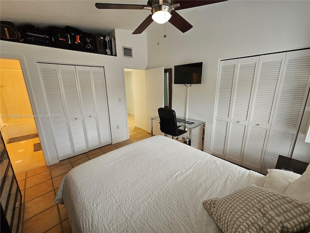 tiled bedroom with multiple closets, ceiling fan, and a high ceiling