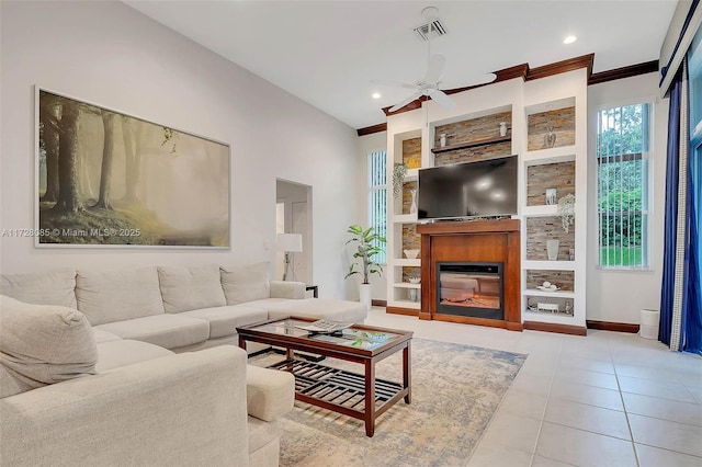 tiled living room with crown molding, built in features, and ceiling fan