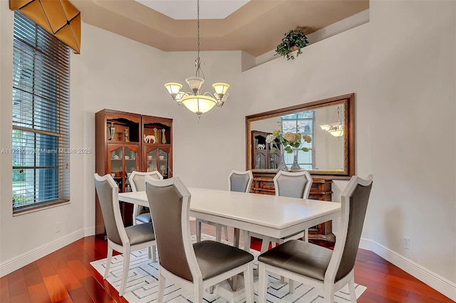 dining area with a high ceiling, hardwood / wood-style floors, and an inviting chandelier