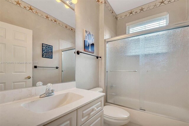 full bathroom featuring enclosed tub / shower combo, vanity, and toilet