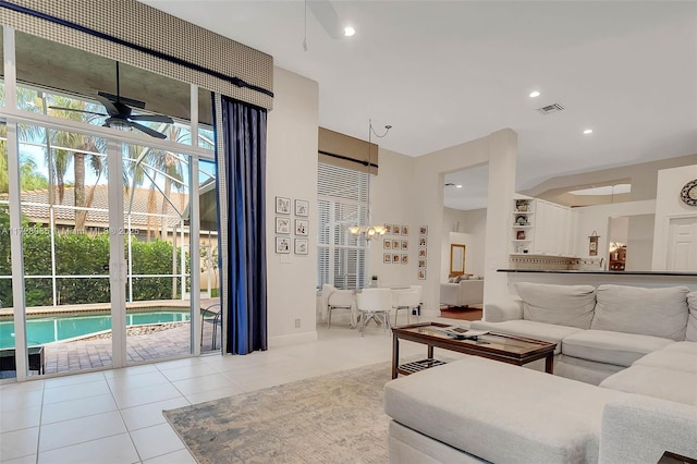 tiled living room with ceiling fan with notable chandelier