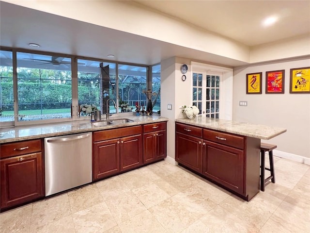 kitchen with a kitchen bar, sink, stainless steel dishwasher, kitchen peninsula, and light stone countertops