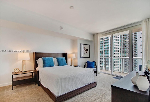 bedroom featuring expansive windows and light carpet