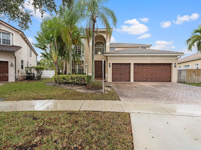 view of front of home featuring a garage, a tiled roof, fence, decorative driveway, and stucco siding