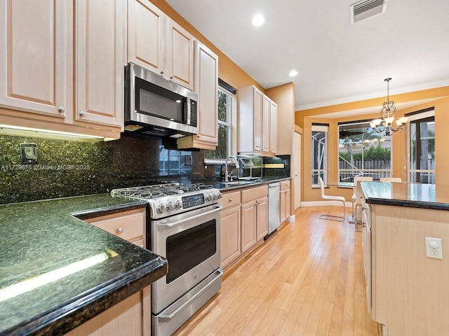 kitchen featuring visible vents, decorative backsplash, appliances with stainless steel finishes, a sink, and light wood-type flooring